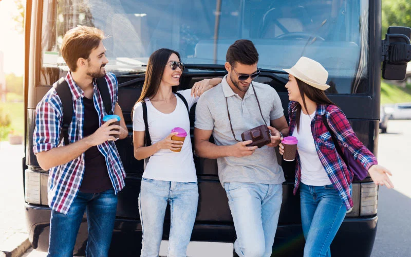 A group of happy travellers boarding a modern coach for a day out coach trip in the UK countryside.