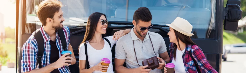 A group of happy travellers boarding a modern coach for a day out coach trip in the UK countryside, day trip transportation