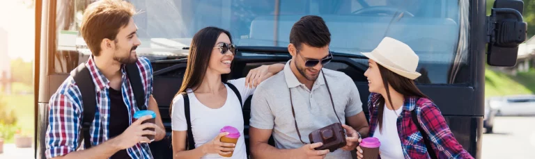 A group of happy travellers boarding a modern coach for a day out coach trip in the UK countryside, day trip transportation